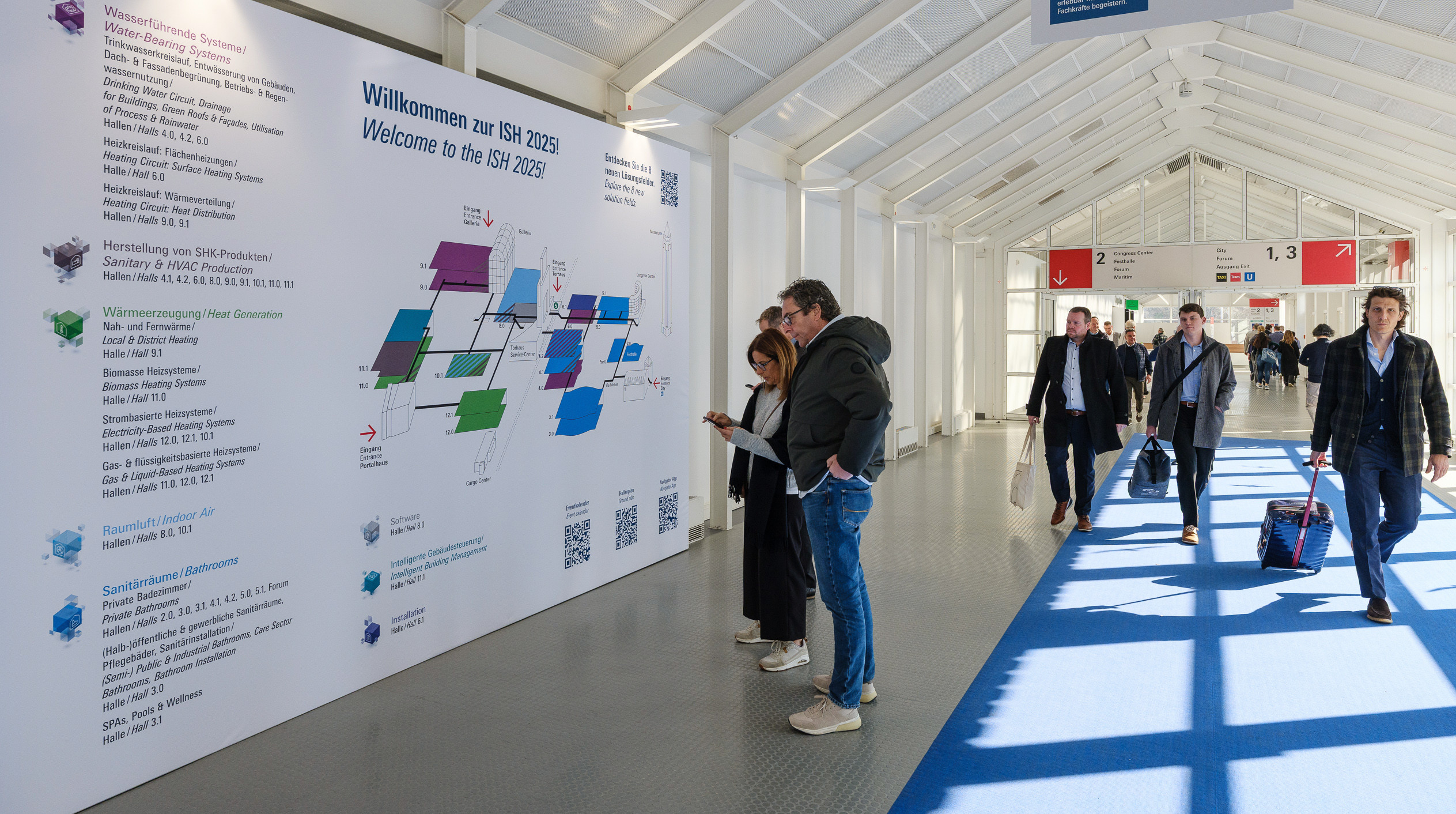 Messebesucher vor einem Geländeplan-Plakat